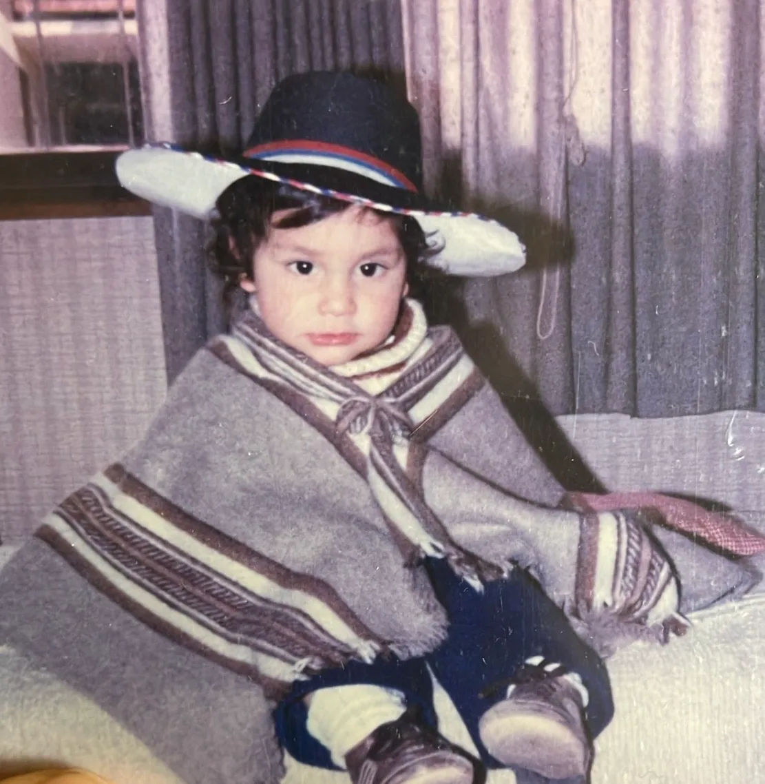 Old photo of Felipe as a toddler, wearing a wool poncho and a dark hat